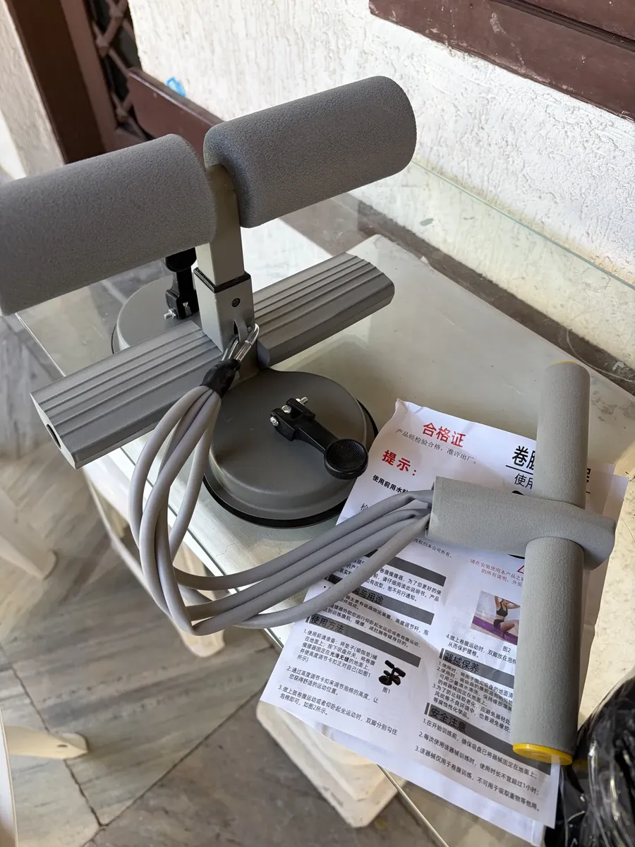 Kit completo com aparelho, elásticos e puxador ao lado do manual